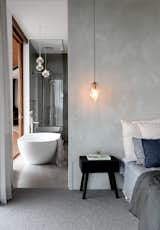 The grayscale tones of the bedroom extend into the adjacent bathroom to create a cohesive backdrop.