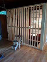 During: New framing awaiting stain replaces solid walls. The closet doorway was filled with a red Shoji-style screen to mark what was there before.