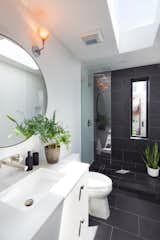 A skylight brightens up the 50-square-foot bathroom, clad in charcoal and white tile. The skylight “really makes the shower feel very much like a sanctuary,” says Thomsen.