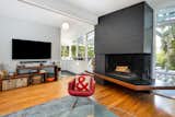 The cantilevered hearth has a distinct geometric shape. Access to the rooftop patio lies between the kitchen and this living room.