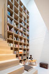 A soaring tower of shelves crafted from Shinnoki pre-finished wood panels in the "Ivory Oak" color now form the family library.