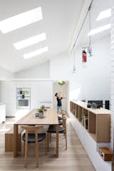 The kitchen’s flat-front white cabinetry seems almost to disappear into the walls, while the wood shelving and floors warm up the "gallery-like" space. An opening placed high on the wall allows the kids to peek down from the attic playroom.