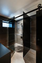 Panels of black glass separate the shower and toilet in the reimagined bathroom.