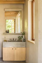 In the bathroom, a concrete sink basin and shelf cast by a local artisan sits over a birch vanity.