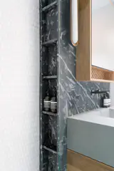 When the wall behind the sink had to be thickened for plumbing, the firm used it as an opportunity to add more shelving.