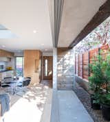 Exposed steel structural elements and cedar siding meet in the side patio, where 27-foot-wide doors merge inside and out. By enlarging the side yard beyond setback requirements, Saez Pedraja made the house more narrow. “But, by making it more narrow, we made the living space bigger,” says the architect.