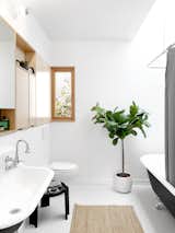 A claw-foot tub is combined with a wall-hung sink and a contemporary medicine cabinet by Kerf, continuing the tension between old and new. A new skylight brings in plenty of sunlight.