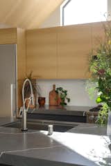The faucet is by Brizo, and the sink is from Kräus. The backsplash is a handmade white ceramic tile that lends some organic irregularity to the scheme.