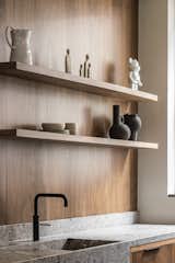 A walnut backsplash has integrated shelves for display. The counter is limestone.