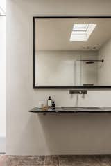 The sleek wall-hung sink is made of Black Marquina and complemented by the texture of the terracotta floor tiles. The clay wall coating has a waterproof finish in the bathrooms.