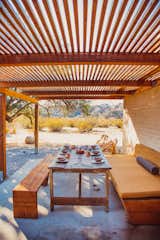 An outdoor eating area is protected from the sun with a pergola.