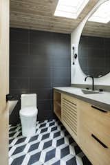 The en suite bathroom has a custom bamboo vanity topped with custom concrete counters. A 48-inch mirror with a matte-black rim syncs with the Kohler fixtures.