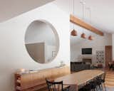 An exposed ridge beam at the ceiling and sloping ceiling defines the living room in the open plan. The lights over the dining table are by Muuto.