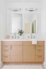 The same white oak cabinetry from the kitchen was used for the double vanity, and topped with a Corian counter.