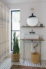 Now, a Sedona Straight Arm Sconce from the Lucent Light Shop illuminates the Enter Mirror from Ferm Living, and the Coyuchi Rippled Stripe Organic Shower Curtain lines the bathtub.
