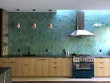 The upper cabinets were removed and replaced with a wall of blue-green handmade tile, with a glaze that reflects the sunlight.