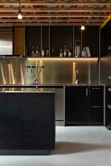 The kitchen cabinets are Birch plywood with medium-pressure laminate, and part of a cabinetry package for the house that amounted to $82,000 NZD, or $55,218 USD. The counters and backsplash are stainless-steel. The kitchen is a favorite spot for the architect. “We do a lot of cooking. We really enjoy our food. So, the practicalities of how the kitchen works is really key, with the nooks and crannies where we can put all our stuff,” says Maclean. Open cubbies keep tools and cookbooks close at hand.