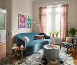 The living room was tucked into the front portion of the parlor floor, with a curved velvet sofa from Crate &amp; Barrel and Terrazzo hand-knotted rug from Nordic Knots defining the space. Unexpected pattern is delivered via the Geometric Prints by Marina Ancona at 10 Grand Press, custom drapery using Imogen Heath Anni Stripe Rose, and the owner’s chair reupholstered in Cutout by HBF Textiles. In a perfect combination of the homeowners, the vintage demilune Italian brass tables were refurbished with pink mirrored plexiglass.