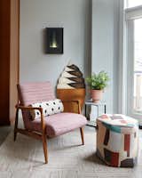At the rear of the home, adjacent to the kitchen, there’s a den and playspace for Leon. For it, the owner’s chair was reupholstered in Pollack fabric ‘Reflex, Dragonfruit,’ and placed with a hexagonal ottoman from The Inside. The ice cream art was a gift from one wife to the other.