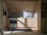 Custom oak cabinetry and marble counters and backsplash define the small kitchen in the open plan. The rug is by Armadillo &amp; Co.