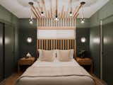 Boudreau incorporated the window into the wood slat headboard design, which “ribbons” out to custom pendant lights suspended from the ceiling. The nightstands are from Crate &amp; Barrel, and provide striking contrast with the dark paint, “Ecological” by Dunn Edwards.