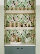 The revamped bar repeats the treatment from the kitchen, including a Fenix cabinet, quartz counter, and Schoolhouse hardware. The wallpaper is the Arcadia Pink Banana Leaf pattern by Kenneth James.