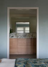 Honed Calacatta Monet marble counters adorn a custom white oak vanity with limestone tile floors.