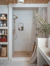 Since micro-cement is waterproof, Curtis also used it to cover the shower walls, dispensing with the need for tile and the busyness of grout lines. A full-height linen shower curtain adds more texture and movement, and the plumbing is handmade of brass.