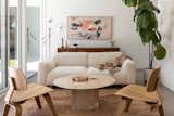 A vintage rug sits with a Koti Sofa by Hem, reproduction Eames moulded plywood chairs, and a vintage travertine table from Midcentury LA. The credenza is also vintage, with the artwork above it by Maja Dlogolecki.