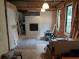 During: This shows how the couple installed a dividing wall with a fireplace to anchor one end of the living room. Behind it is the laundry and powder room. During demolition, they discovered two large windows that had been boarded up and covered by cabinets and the refrigerator.