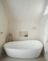 An asymmetrical Porcelanosa bathtub is tucked into its own niche.