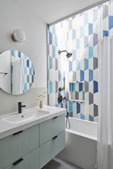 An IKEA vanity has Semihandmade cabinet doors, with a Kohler Elate deck mounted faucet at the sink. Nemo Strada floor tile complements Popham cement tiles in the shower, now lit by a skylight.