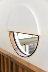 A round window at the top of the stairs is trimmed in walnut and brings in natural light.