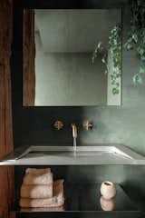 A stainless steel, wall-mounted sink appears to float, as does the steel shelf below, and the pipes are hidden in the wall.