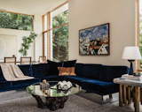 The living room has a vintage Milo Baughman couch with cushions fashioned from Angora mohair from Architex. The coffee table is vintage, as is the side table base, given a custom stone top. A Seneca Table Lamp is by Danny Kaplan, while the artwork over the couch is by Patton Miller.