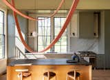 It was important, says Kaplan, to define the kitchen area with the “heavy horizontal lid” that runs along the top of the windows. The custom stove hood echoes the lines of the original wainscot.