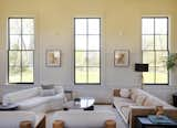 In the living room, a white sofa from Maria Yee and CB2 couch flank a custom coffee table designed and built by Joel. The walls are painted “Schoolhouse White” by Farrow &amp; Ball, and the windows are Benjamin Moore “Mopboard Black.” The windows have custom storm windows for improved energy efficiency.