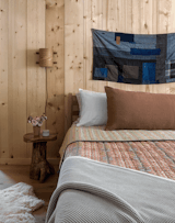 Vintage stump side tables from Facebook Marketplace sit beneath Lichen’s Sconce No. 1 by Aidan Elias. The wall art is a vintage Japanese Boro-patched Sashiko Quilt.