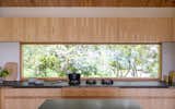 Kitchen, Refrigerator, Wall Oven, Wood Cabinet, Cooktops, Light Hardwood Floor, and Stone Counter SHED specified a new horizontal window above the stovetop to create a vignette of the surrounding foliage.