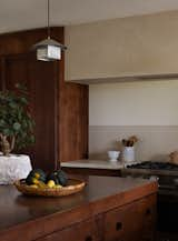 The Lin Pendant by Muhly hangs over the island. The counters and backsplash are concrete.