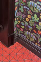 The color progression starts in the entry, with FireClay 3-inch triangle tile in orange-red Ember and Svenskt Tenn's Wallpaper Vårklocker by Josef Frank.