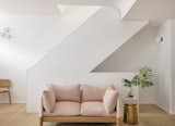 Now the rebuilt staircase is a sculptural backdrop to the living room, which gained more space and natural light. The Tepee Sofa is by Lucy Kurrein, and the brass stool by Hem. The floors are Madera Belgian Oak.