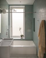 Shahane changed the layout and in so doing, restored the window to its original larger size. Heath Ceramics tile wraps the room, Stone White on the floor and Modern Blue on the walls. A Foscarini Gregg sconce hangs above the Azzura Ceramica Elegance Squared sink.