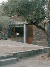 A concrete lintel and post marks the new window and door in the facade. The building's position makes inhabitants feel like they are hunkered down in the olive grove.