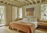 Now the ceiling framework gives the room more height, and two taller window units flank either side of the bed, adding to the illusion of more height. Pendants by Poul Henningsen for Louis Poulsen hang above the custom white oak bed designed by Lake Flato Architects.
