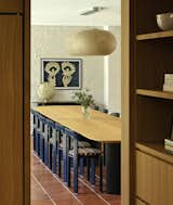 The interior designers hung a Puffball Cloud Pendant chandelier by Faye Toogood over the extra-long dining table by Miniforms, and surrounded it with blue chairs by Bruno Rey upholstered with Pierre Frey fabric. "One of the things the client wanted was a lot of energy and color,