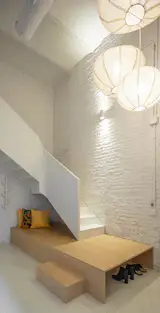 The wooden platform at the base of the staircase doubles as seating and storage.