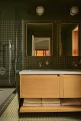 Fireclay Peabody tile covers the bathroom, with Luminaire Authentik Norvégienne sconces, Rubinet faucets, and Pottery Barn medicine cabinets.