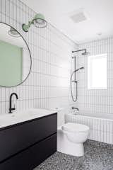 Subway tile meets graphic Terrazzo-like porcelain tile in the family bathroom, with a Jielde sconce.