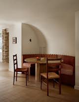 The custom walnut banquette surrounds a vintage travertine table.